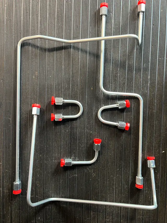 Assorted JIC 37° hydraulic tube assemblies with installed nuts and red protective caps, including U-bends and multi-plane bends