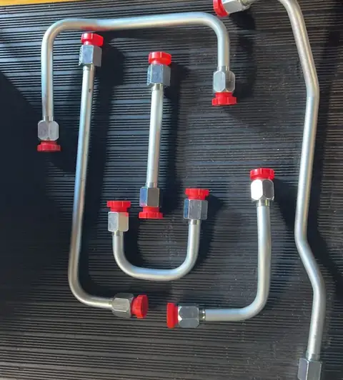 Six different JIC hydraulic tube assemblies with nuts and red caps on a ribbed mat